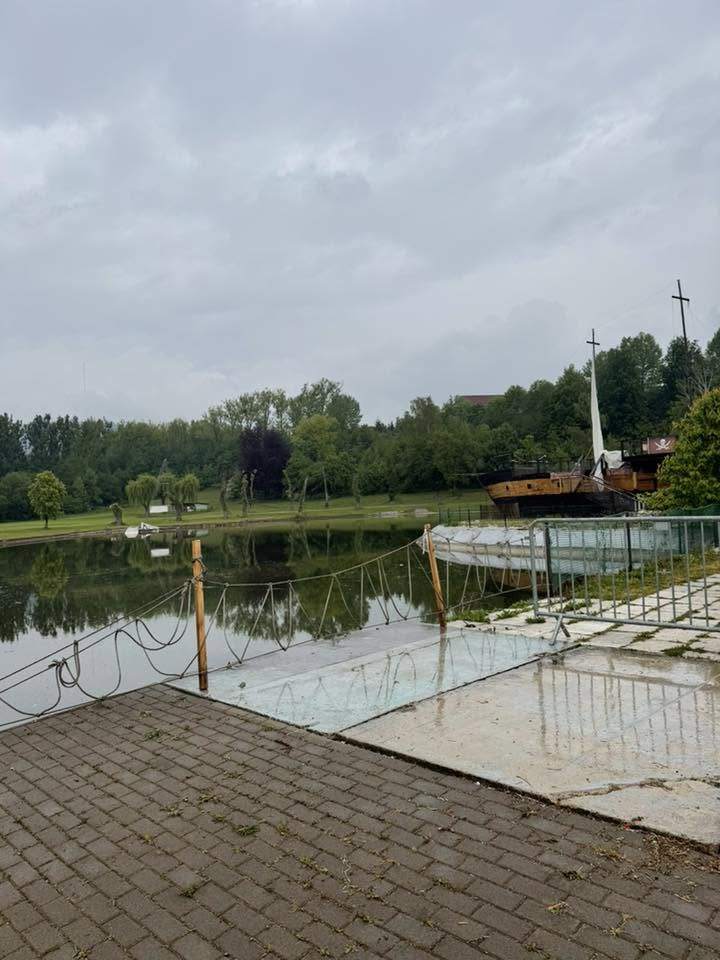 Jazero so zelenkavou vodou a plávajúcou plošinou, v pozadí drevená loď