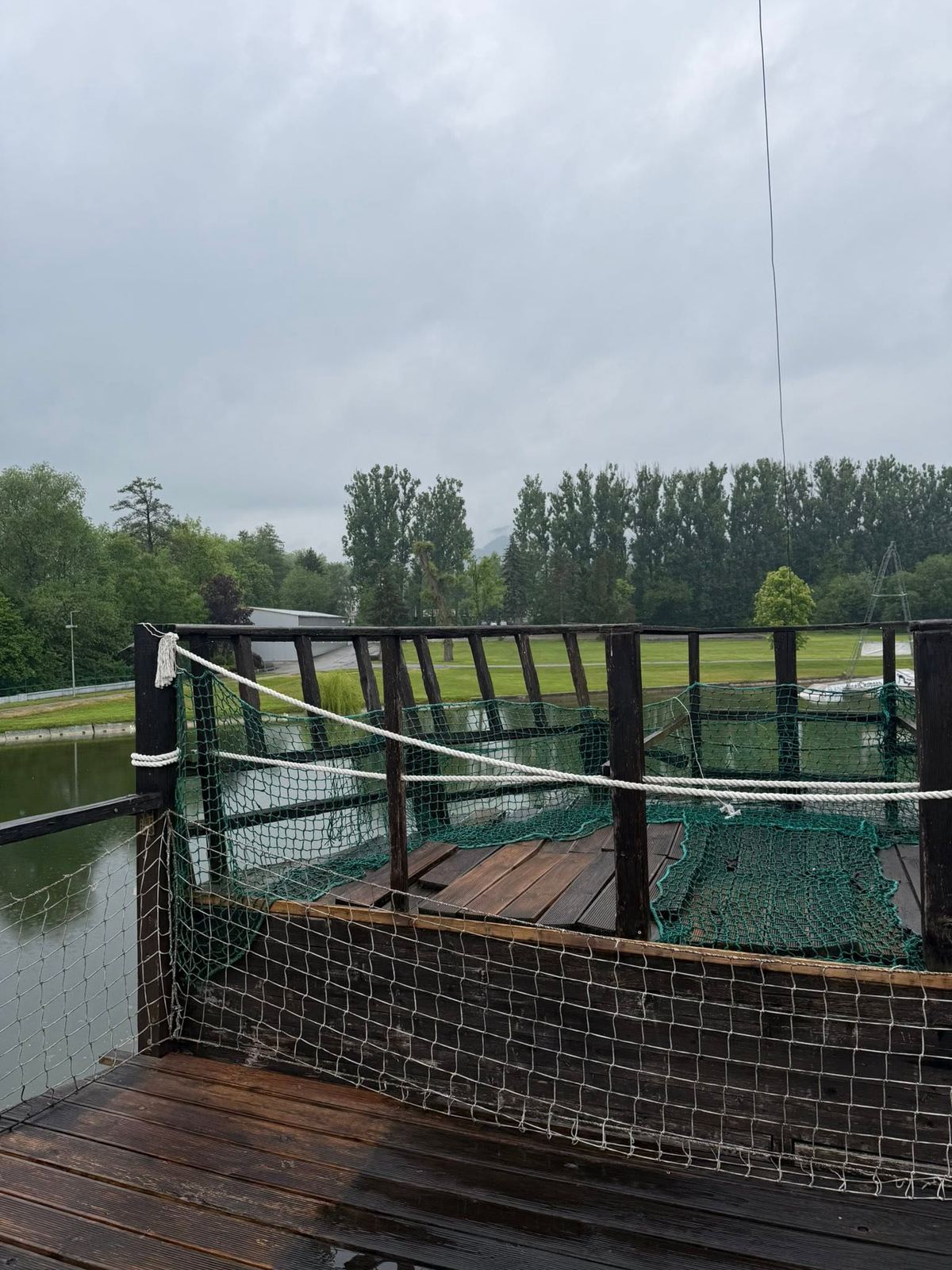 Drevená plošina so sieťou nad jazerom, doskový povrch je zvetraný